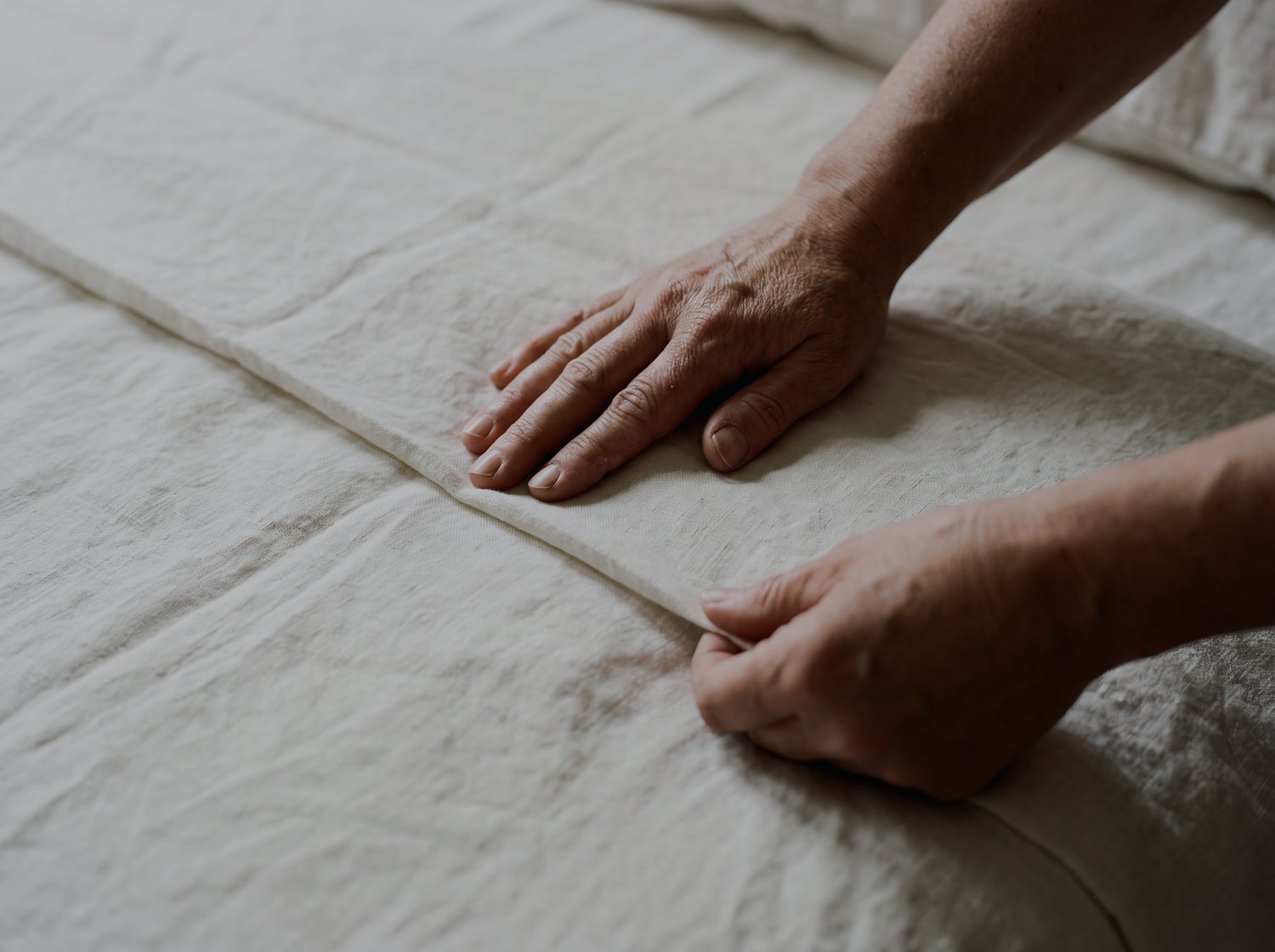 Hands smoothing fresh linen during a turn