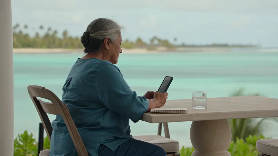 Illustration: a host on a seaside terrace reads a message on her phone.